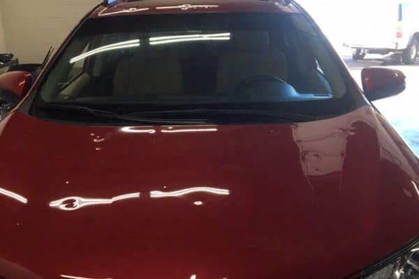 Hail damage on red car